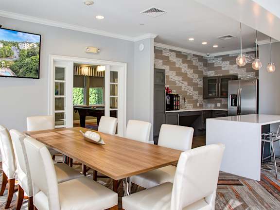 A modern dining room with a wooden table and white chairs.