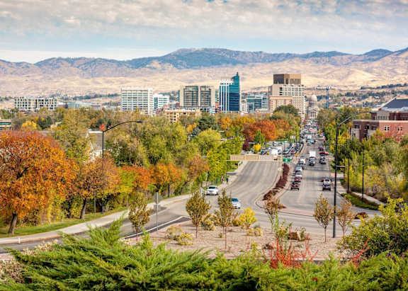 A city street with cars and trees in autumn colors.