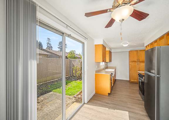A kitchen with a refrigerator, oven, and a ceiling fan.