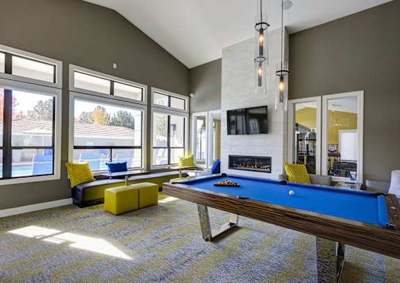 A pool table in a room with a fireplace and a television.