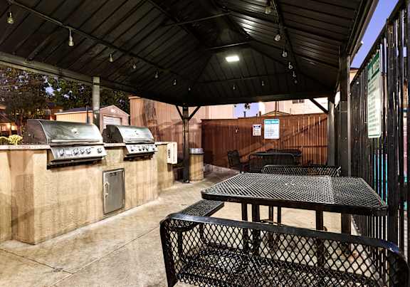 A patio with a table and chairs under a roof.