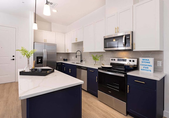 A kitchen with a white counter top and dark blue cabinets.