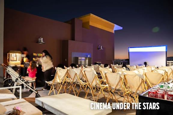 A group of people are sitting in chairs outside at night watching a movie under the stars.