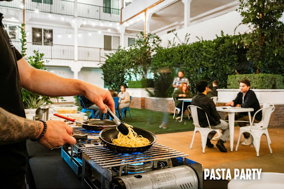 A man is cooking pasta at a pasta party.