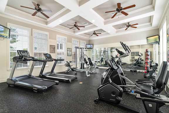 a gym with cardio machines and ceiling fans