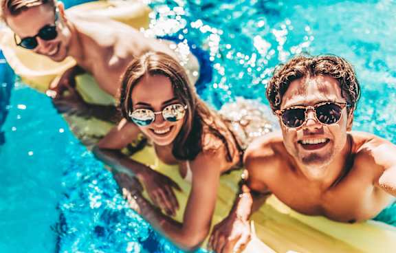 Three people are enjoying a sunny day in a pool.