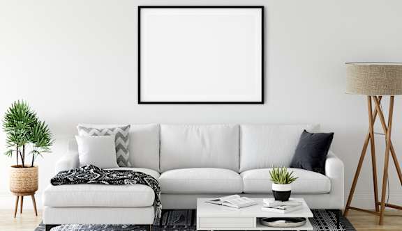 A living room with a white couch, a potted plant, and a coffee table.