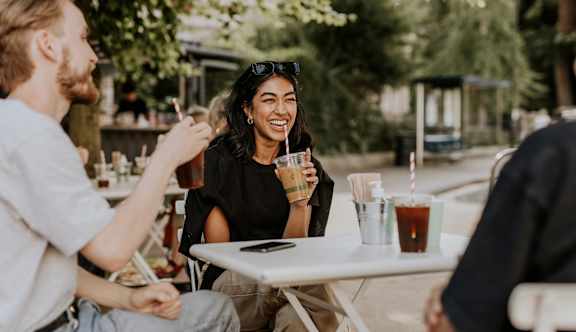 A man and a woman are sitting at a table with drinks, enjoying a conversation.