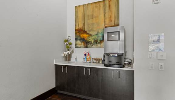 A grey counter with a vase of flowers and a coffee machine on it.