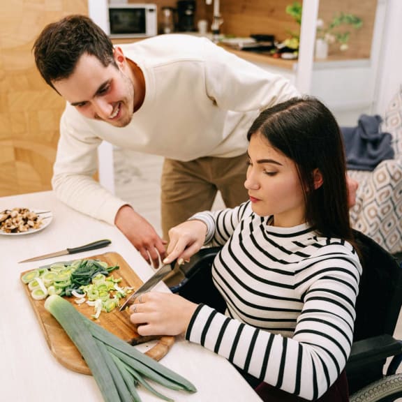 a man cutting a salad with a woman sitting at a table