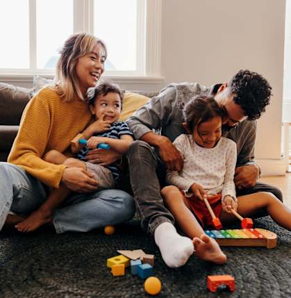 Family Smiling and Playing with Toys on Ground in Living Room