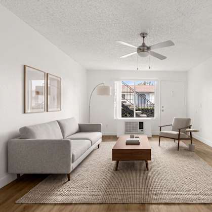 A living room with a grey couch, a brown coffee table, and a ceiling fan.
