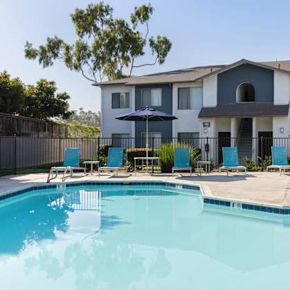 A swimming pool in front of a multi-story apartment building.