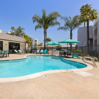 A swimming pool surrounded by chairs and umbrellas.