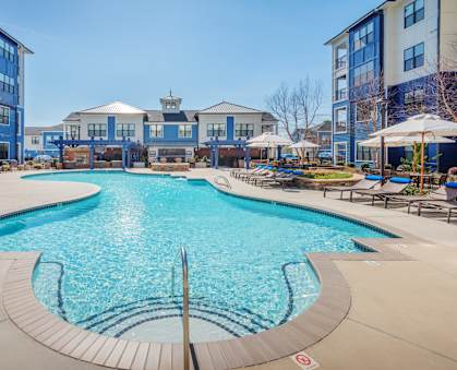 a swimming pool with lounge chairs and umbrellas at Streets of Greenbrier in Chesapeake, VA 23320