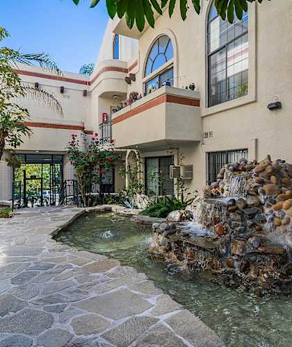 A stone fountain is in the middle of a courtyard.