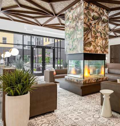 Community lobby with 360 degree fireplace at Stella Apartments in New Carrollton, MD
