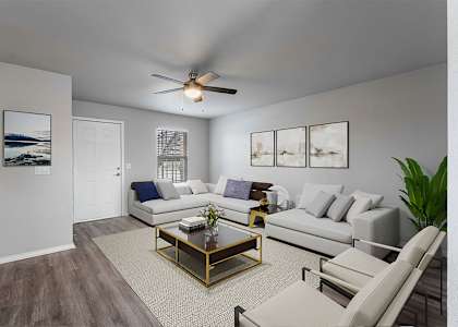 A living room with a white couch, a coffee table, and a ceiling fan.