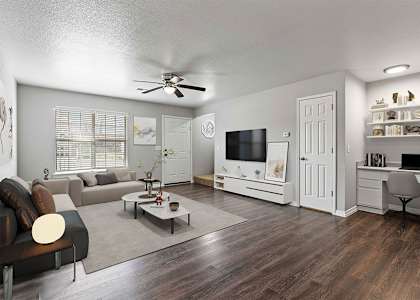 A living room with a couch, a coffee table, a television, and a desk.