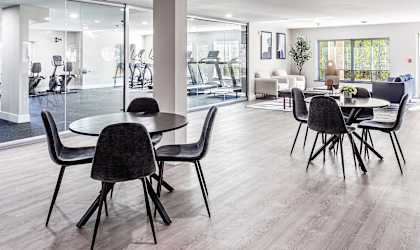 a communal area with tables and chairs and a living room with glass doors