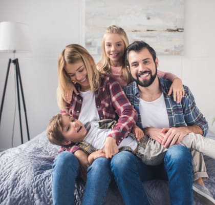 Family Smiling while Sitting on Bed Together
