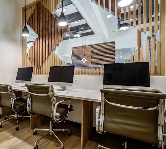 a conference room with computers and chairs and a staircase