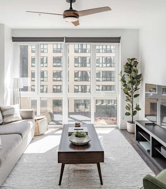 A living room with a grey couch, a coffee table, a green chair, and a painting on the wall at Anthem House Apartment, Huntsville, AL, 35806