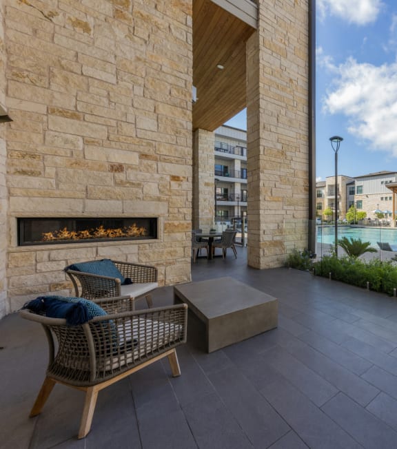 a patio with chairs and a fireplace next to a pool