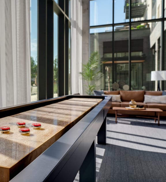 a shuffleboard table in the lobby of a building with large windows at Marquee, Minnesota