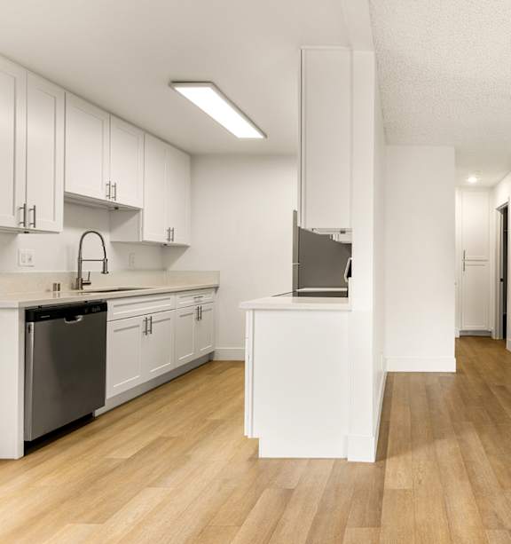 A modern kitchen with a stainless steel refrigerator and a white countertop.