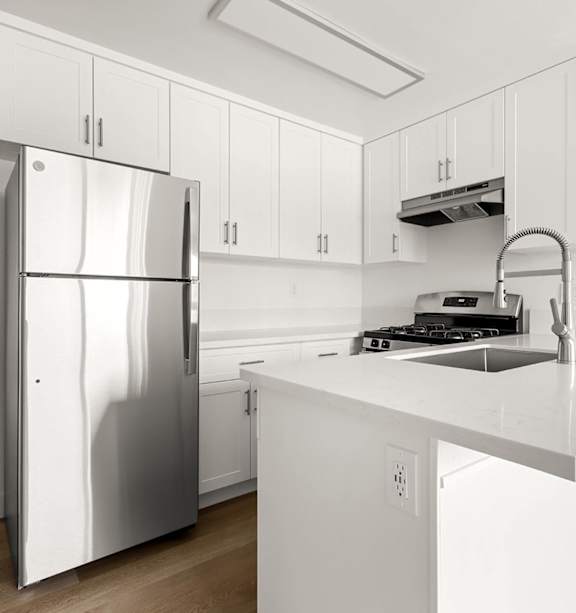 A modern kitchen with a stainless steel refrigerator and a white countertop.