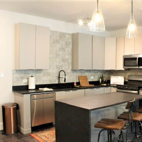 A kitchen with a black counter top and stainless steel appliances. at The Mobile Lofts, Alabama