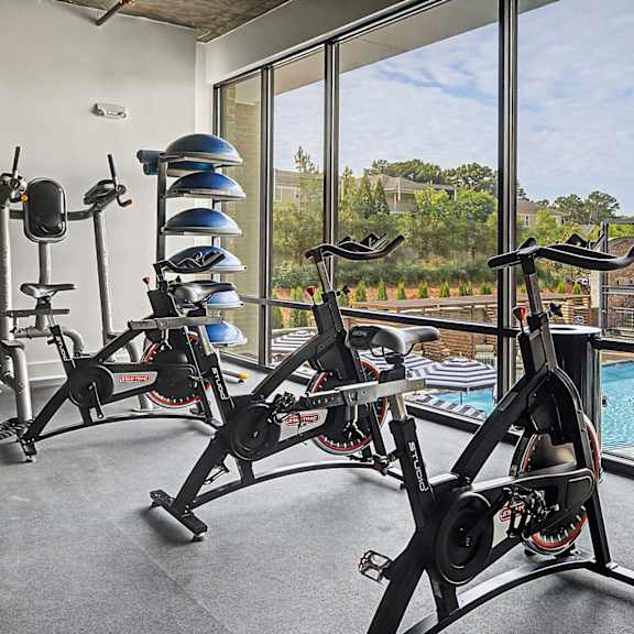 A gym with exercise bikes and a view of a pool.
