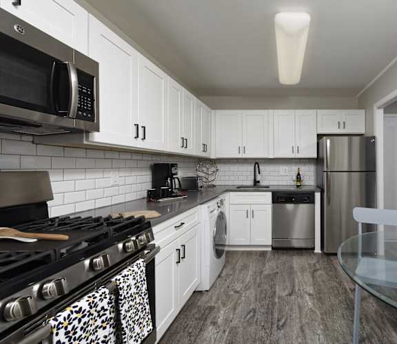 a kitchen with white cabinets and stainless steel appliances and a glass table