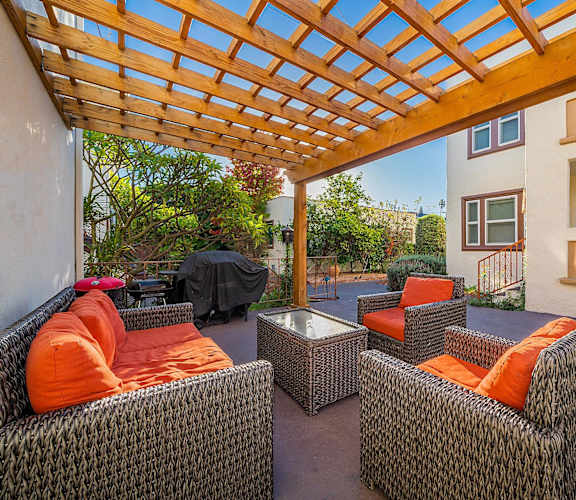 a patio with couches and chairs under a wooden roof