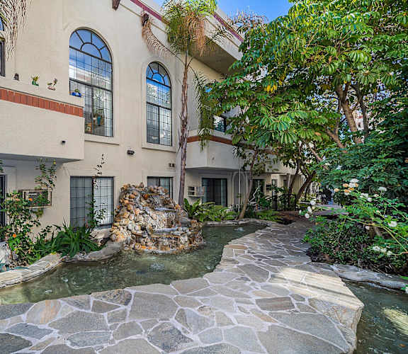 A house with a stone fountain in front of it.