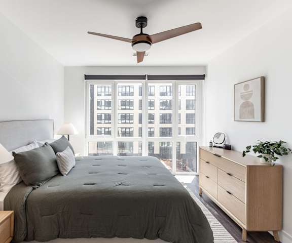 A bedroom with a bed, nightstand, and window overlooking a city at Anthem House Apartment , Huntsville, Alabama