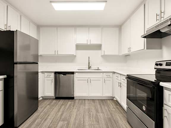A kitchen with a table and chairs in front of a fridge and cabinets.