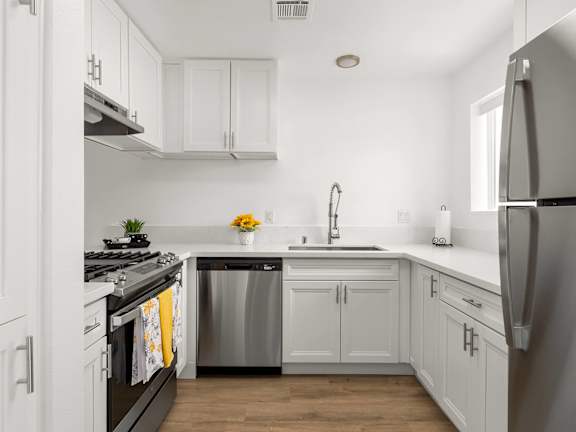 A kitchen with a table and chairs in front of a fridge and cabinets.