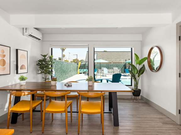 A kitchen with a table and chairs in front of a fridge and cabinets.