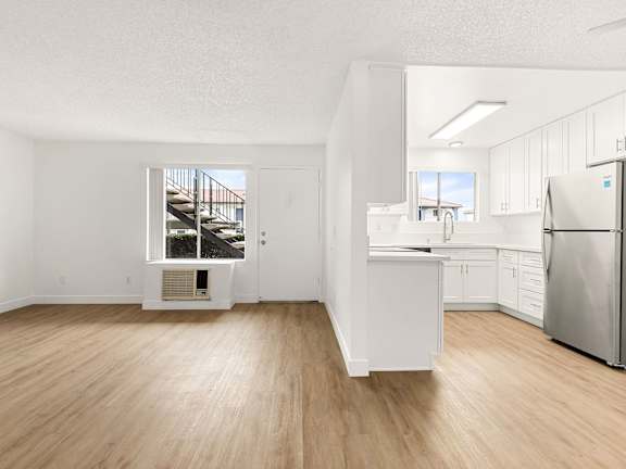 A kitchen with a table and chairs in front of a fridge and cabinets.