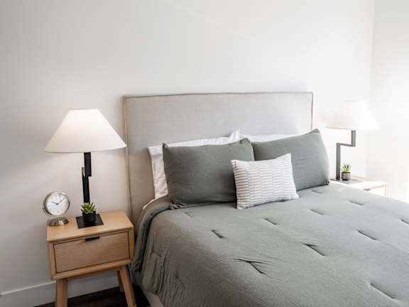 A bed with a grey comforter and pillows is in the image at Anthem House Apartment, Huntsville, AL, 35806