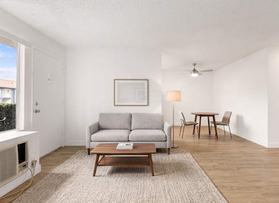A living room with a grey couch, a brown coffee table, and a painting on the wall.