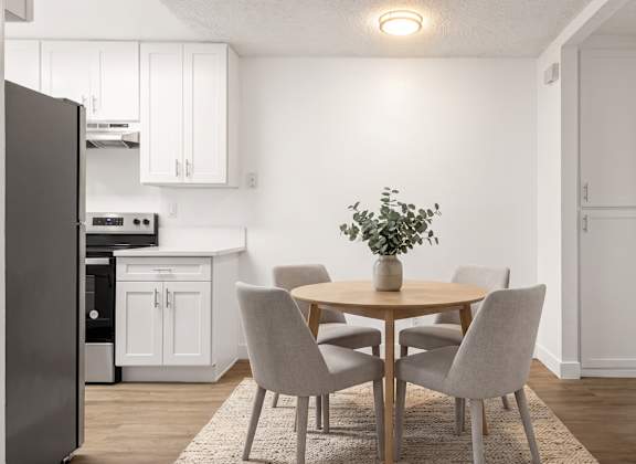 A kitchen with a table and chairs.