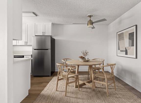 A dining room with a table set for two and a refrigerator in the corner.