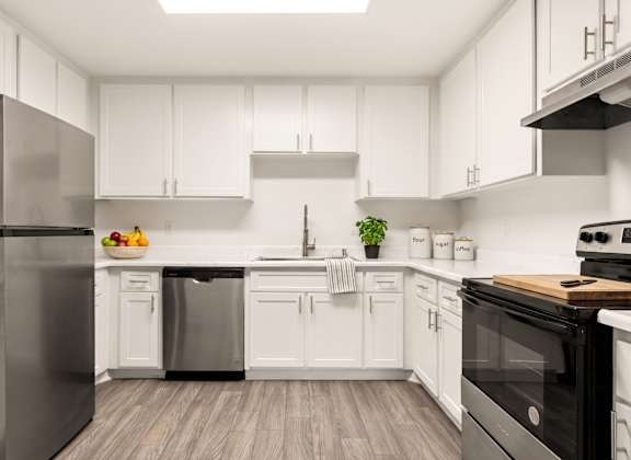 A modern kitchen with white cabinets and stainless steel appliances.