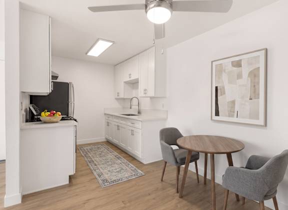 A kitchen with a table and chairs and a fridge.