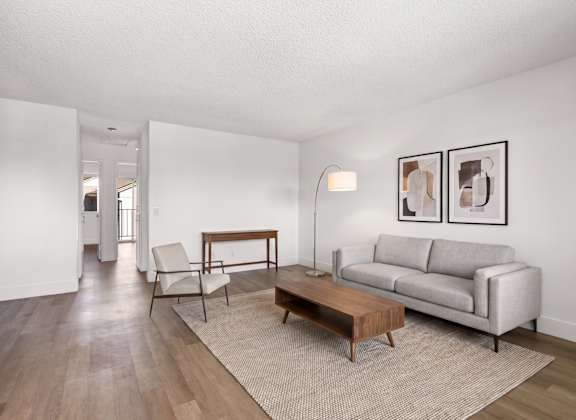 A living room with a grey couch, a wooden coffee table, and a lamp.