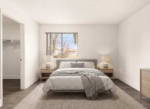 A bedroom with a bed, nightstands, and a window.