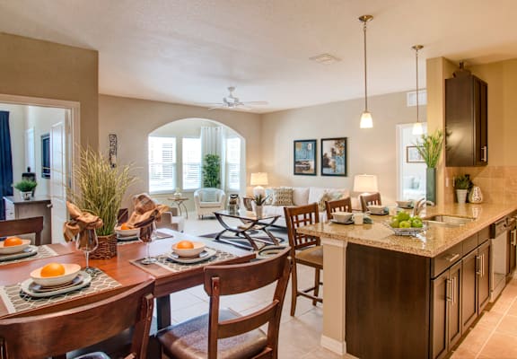 a kitchen and living room with a dining room table and chairs